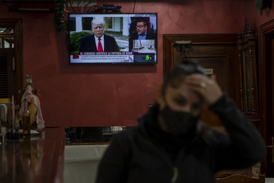 A waiter gestures in front a TV screen broadcasting news reports on U.S. President Donald Trump, in Rivas Vaciamadrid, Spain, Thursday, Jan. 7, 2021. Congress confirmed Democrat Joe Biden as the presidential election winner early Thursday after a violent mob loyal to President Donald Trump stormed the U.S. Capitol in a stunning attempt to overturn America&#039;s presidential election.