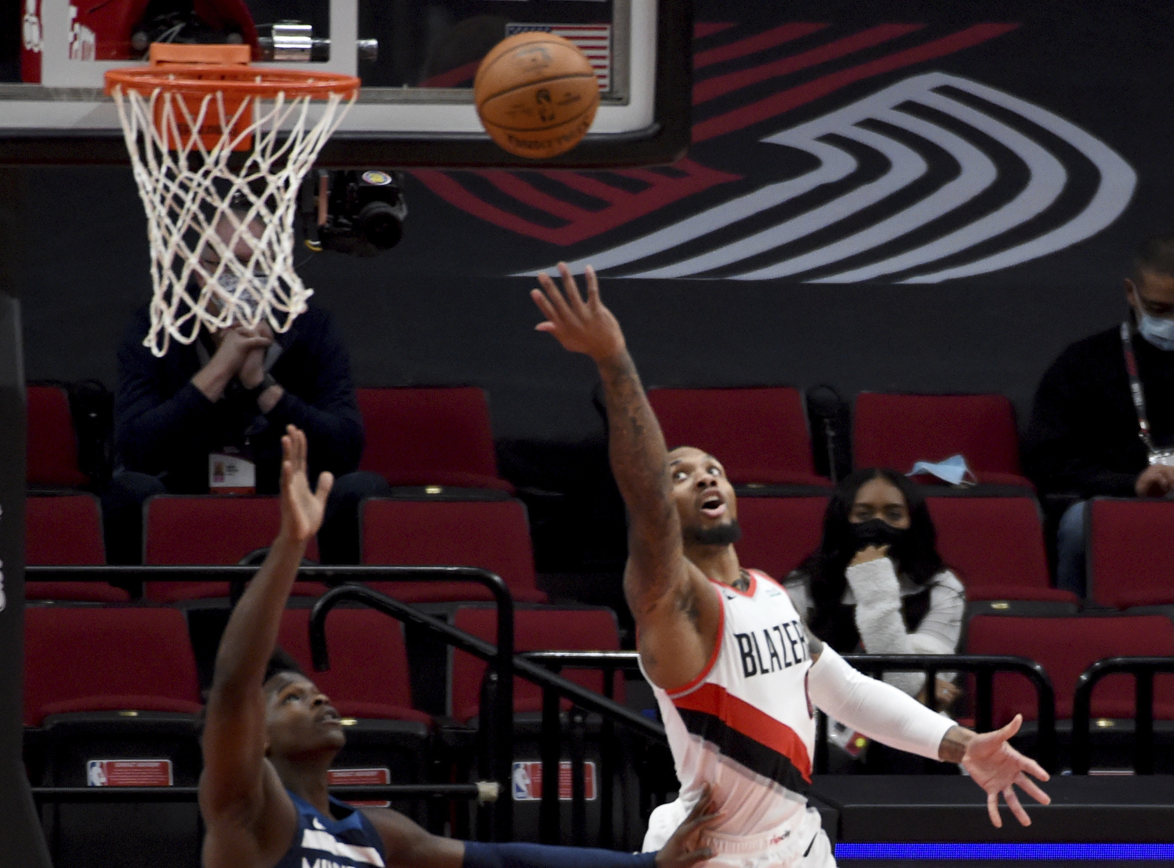 Portland Trail Blazers guard Damian Lillard, right, lays the ball in over Minnesota Timberwolves guard Anthony Edwards, left, during the first half of an NBA basketball game in Portland, Ore., Thursday, Jan. 7, 2021.