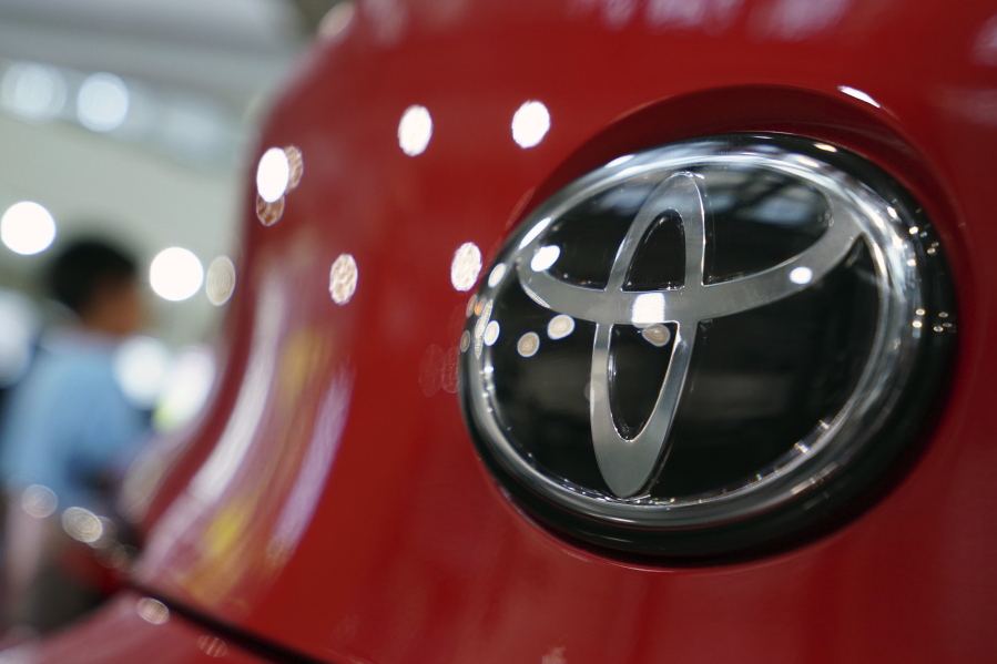 FILE - In this Aug. 2, 2019, file, photo, people walk by the logo of Toyota at a show room in Tokyo. Toyota will pay $180 million to settle U.S. government allegations that it failed to report pollution control system defects in its vehicles for a decade. The company, on Thursday, Jan. 14, 2021,  also agreed in court to investigate future emissions-related defects quickly and report them to the U.S. Environmental Protection Agency in a timely manner.