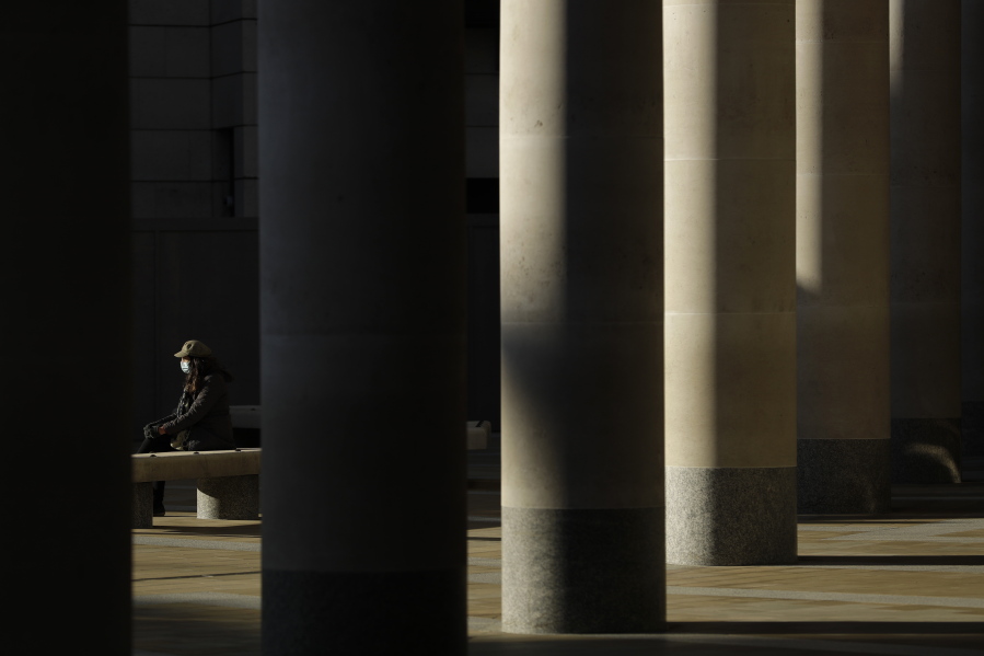 A woman wearing a face mask to curb the spread of coronavirus sits in the sun in Paternoster Square, in the City of London financial district of London, Friday, Jan. 22, 2021, during England&#039;s third national lockdown since the coronavirus outbreak began. Nearly a year to the day after Wuhan went into lockdown to contain a virus that had already escaped, President Joe Biden began putting into effect a new war plan for fighting the outbreak in the United States, Germany topped 50,000 deaths, and Britain closed in on 100,000.