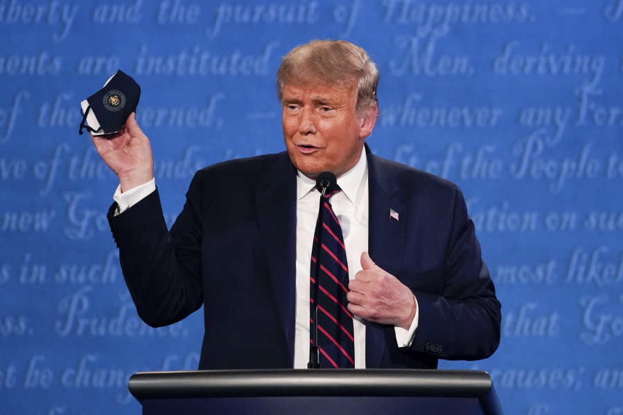 FILE - In this Sept. 29, 2020, file photo, President Donald Trump holds up his face mask during the first presidential debate at Case Western University and Cleveland Clinic, in Cleveland, Ohio. The U.S. death toll from the coronavirus has eclipsed 400,000 in the waning hours in office for Trump.