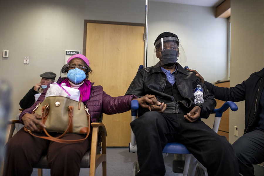 FILE - In this Jan. 23, 2021, file photo, Dorothy Kade, left, holds the hand of her husband, Walter Kade Jr., as they wait in the observation room after he received a COVID-19 vaccine at the VA Medical Center, in Philadelphia.