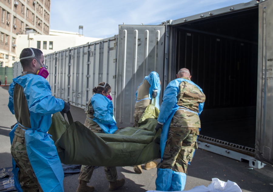 FILE - In this Jan. 12, 2021 photo provided by the Los Angeles County Department of Medical Examiner-Coroner, National Guard members assisting with processing COVID-19 deaths, placing them into temporary storage at the medical examiner-coroner&#039;s office in Los Angeles. The seven-day rolling average of daily deaths is rising in 30 states and the District of Columbia, and on Monday, Jan 18, 2021, the U.S. was approaching 398,000, according to data collected by Johns Hopkins University, by far the highest of any country in the world.