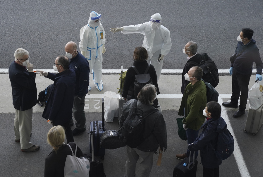 A worker in protective coverings directs members of the World Health Organization (WHO) team on their arrival at the airport in Wuhan in central China&#039;s Hubei province on Thursday, Jan. 14, 2021. A global team of researchers arrived Thursday in the Chinese city where the coronavirus pandemic was first detected to conduct a politically sensitive investigation into its origins amid uncertainty about whether Beijing might try to prevent embarrassing discoveries.