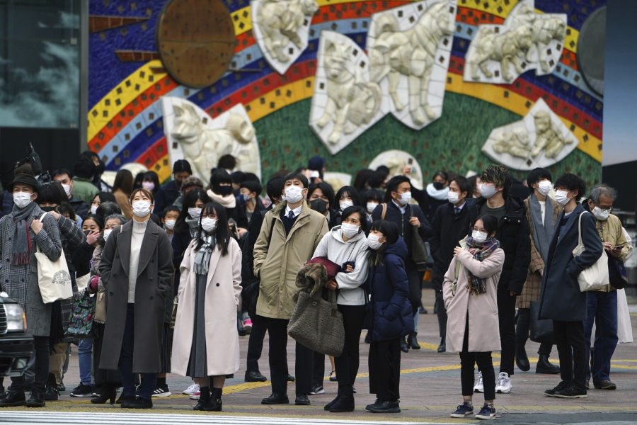 People wearing protective masks to help curb the spread of the coronavirus wait for traffic light to walk along pedestrian crossings in the Shibuya area of Tokyo Tuesday, Jan. 5, 2021. Japanese Prime Minister Yoshihide Suga says vaccine approval is being speeded up to curb the spread of the coronavirus, and he promised to consider declaring a state of emergency. The Japanese capital confirmed more than 1200 new coronavirus cases on Tuesday.