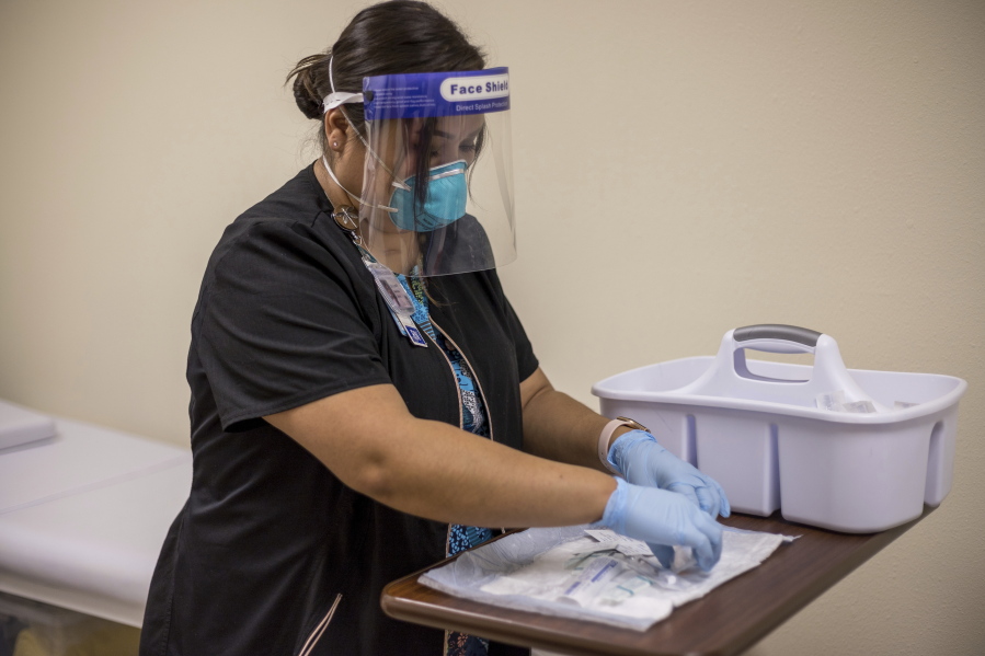 In this Tuesday, Dec. 29, 2020, photo provided by Johns Hopkins Center for American Indian Health, registered nurse Starla Garcia prepares a coronavirus vaccine in Chinle, Ariz., for someone who enrolled in the COVID-19 vaccine trials on the Navajo Nation and initially received a placebo.