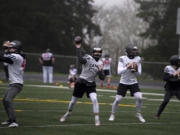 Camas quarterbacks, including Nathan Criddle, left center, and Jake Blair, right center, throw during a drill on Monday at Camas High School. Official practices began across Clark County on Monday as the return of high school sports nears.