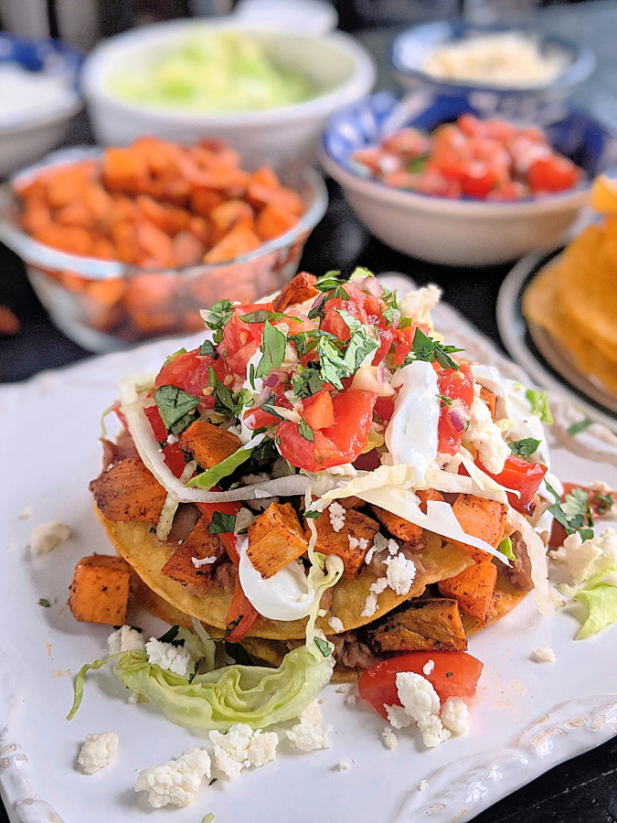 These vegetarian tostadas are stacked with two layers of smashed pinto beans, lettuce, pico and roasted sweet potatoes and bell peppers. Crumbled queso fresco and lime crema add the crowning touch.