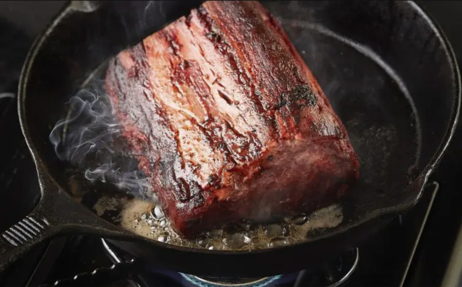 A 3D printed steak sizzles in a pan.