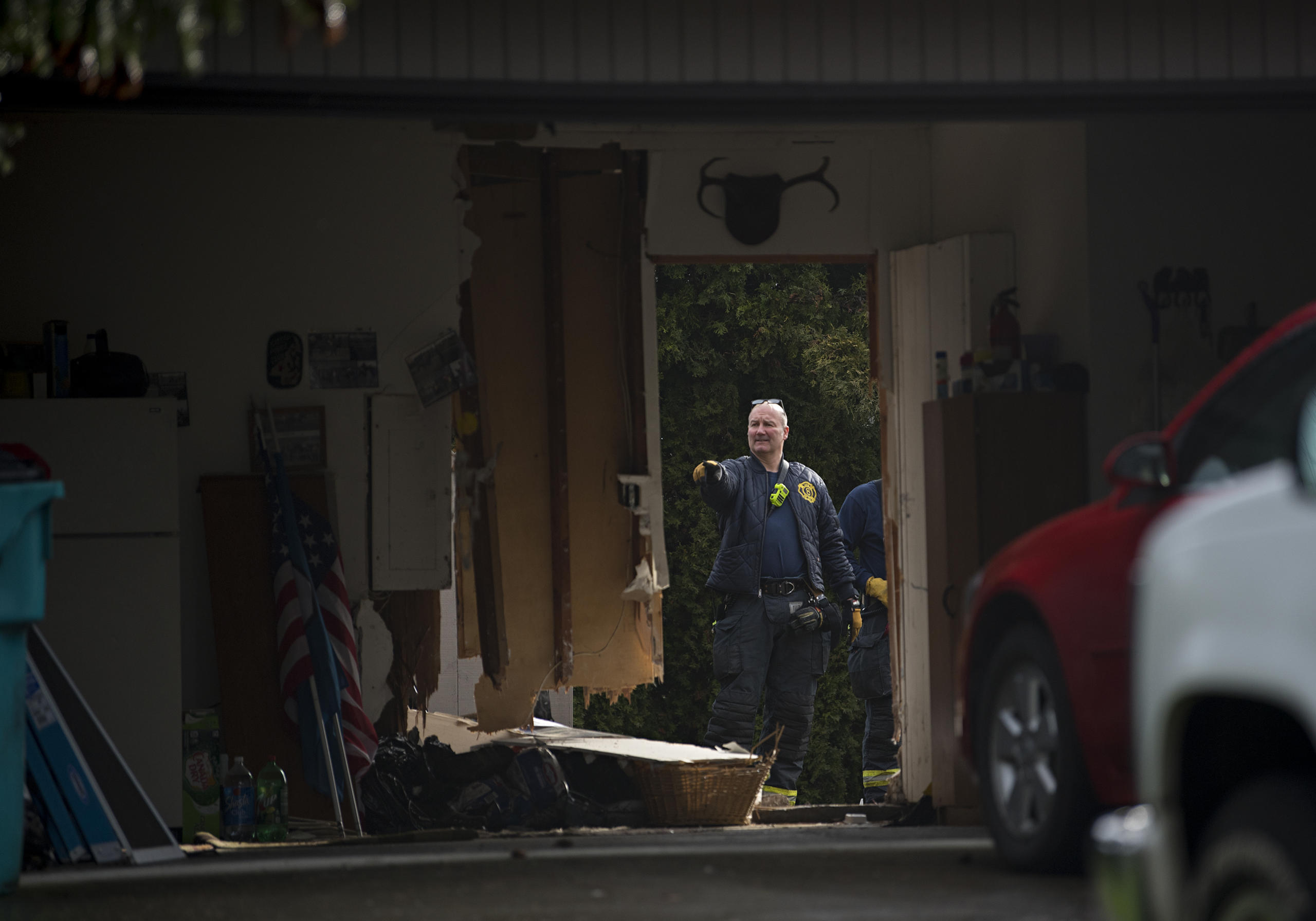 Officials look over the scene after a person reportedly drove through a garage on Northeast 98th Avenue, out the back fence and across Marrion School Park before abandoning the vehicle nearby Friday morning, Feb. 18, 2021. Police are still looking for the driver.