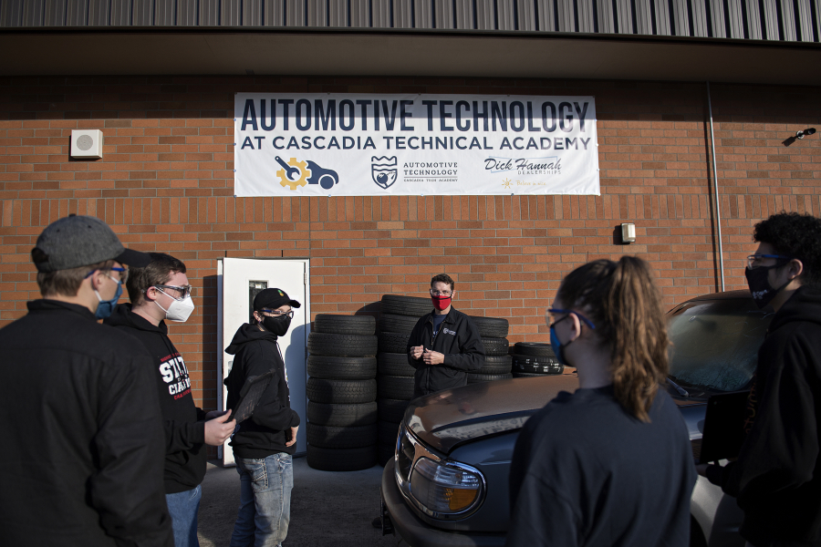 Automotive instructor Adam Eldridge, center in red mask, works with students as they prepare to push a car inside the auto shop at Cascadia Tech Academy. Remote learning has been a challenge for students learning hands-on occupations.