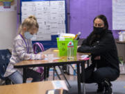 Kindergartner Knightley Wells does a math assignment while educational assistant Tiffany Shimmin observes last month at Captain Strong Primary School in Battle Ground.