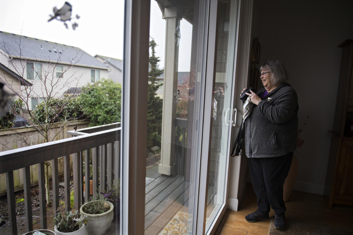 Veteran birder Susan Setterberg keeps an eye out for feathered friends as they fly near her backyard at her Ridgefield home Thursday morning. She will join the Great Backyard Bird Count this weekend.