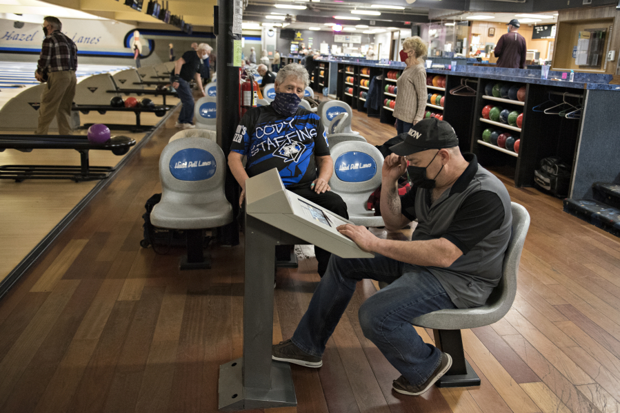 Rick Enge of Camas, in blue and black, joins Robert Black of Vancouver, right, as they keep track of the score at Hazel Dell Lanes on Wednesday. Hazel Dell Lanes reopened this week following the end of a three-month period of increased business restrictions prompted by a rise in COVID-19 cases.