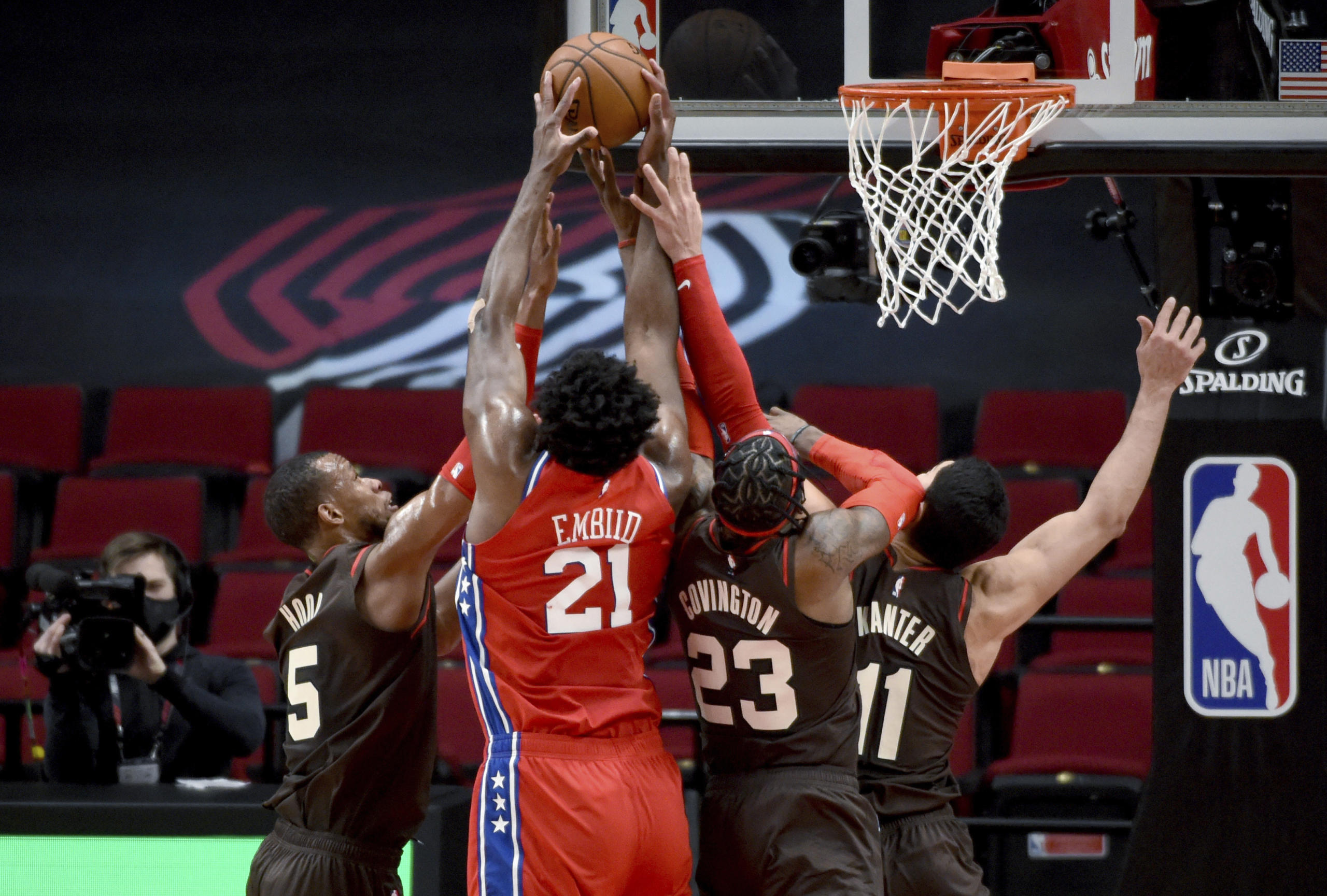 Philadelphia 76ers center Joel Embiid (21) goes after a rebound with Portland Trail Blazers guard Rodney Hood, left, forward Robert Covington, center, and center Enes Kanter, right, during the first half of an NBA basketball game in Portland, Ore., Thursday, Feb. 11, 2021.