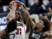 Arizona guard Terrell Brown Jr. (31) gets squeezed into a miss by Washington State center Dishon Jackson (21), left, and guard Isaac Bonton during the first half of an NCAA college basketball game Thursday, Feb. 25, 2021, in Tucson, Ariz.