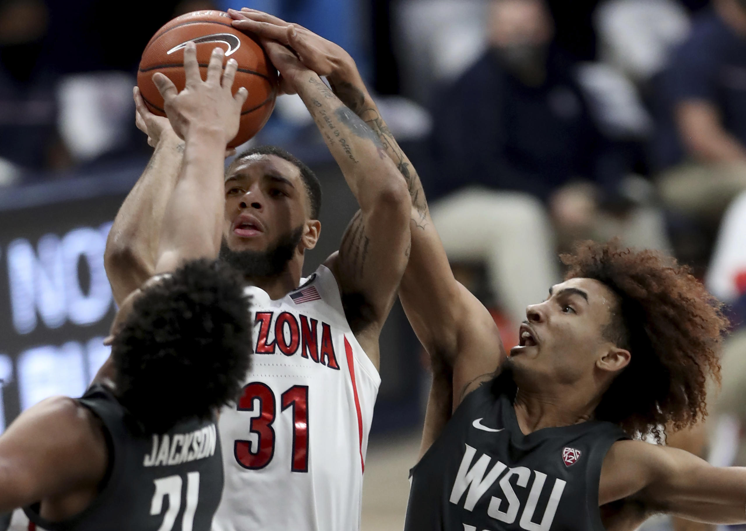 Arizona guard Terrell Brown Jr. (31) gets squeezed into a miss by Washington State center Dishon Jackson (21), left, and guard Isaac Bonton during the first half of an NCAA college basketball game Thursday, Feb. 25, 2021, in Tucson, Ariz.