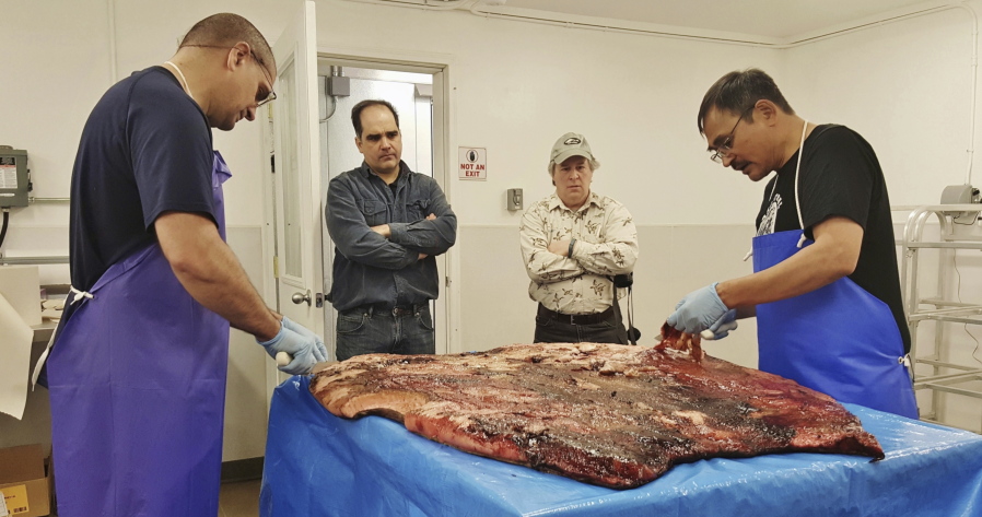 Alex Whiting, left, and Cyrus Harris, right, are observed by Chris Sannito, second from left, and Brian Himelbloom, third from left, of the Kodiak Seafood and Marine Science Center on Oct. 28, 2016, as they trim and clean seal blubber in Kotzebue, Alaska. The Alaska Department of Environmental Conservation approved seal oil to be served at a Maniilaq elder care home, believed to be a first for seal oil in the U.S.