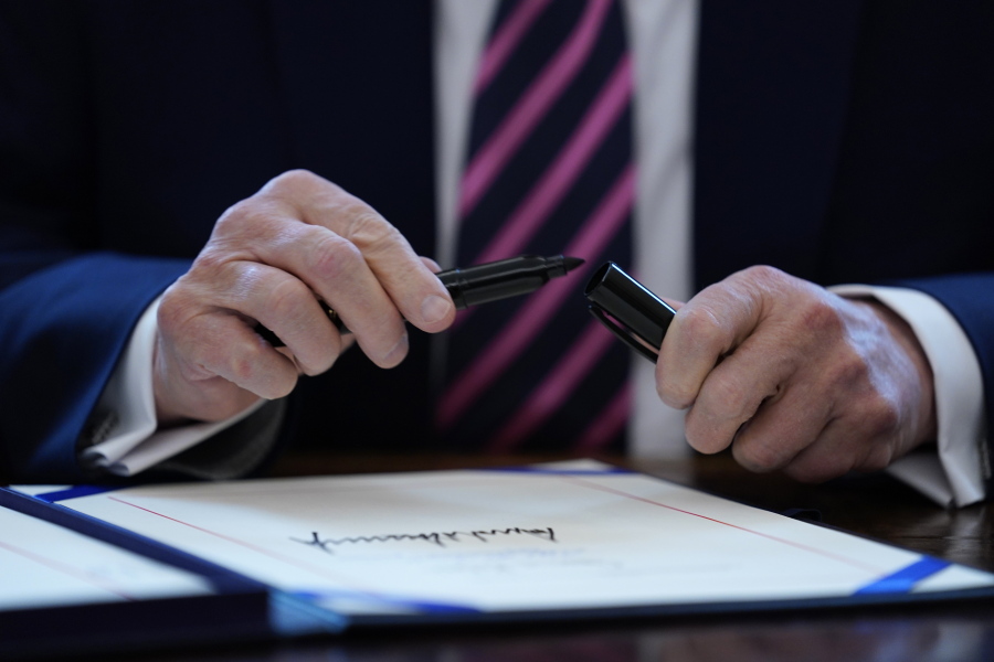 President Donald Trump puts the cap on a pen April 24 after signing a coronavirus aid package to direct funds to small businesses, hospitals, and testing, in the Oval Office of the White House in Washington.