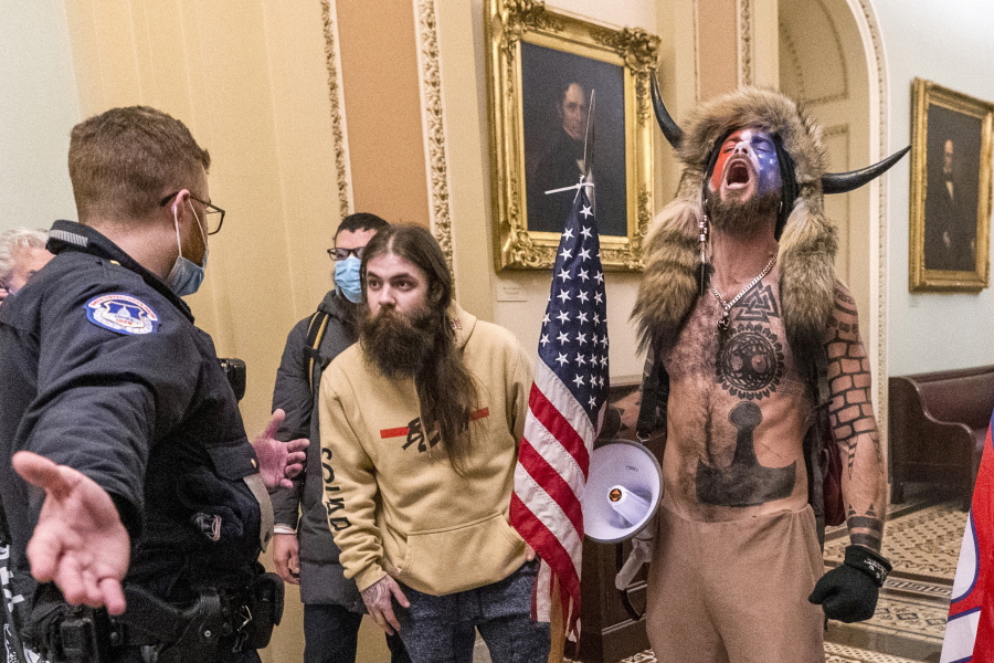 FILE - In this Wednesday, Jan. 6, 2021 file photo, supporters of President Donald Trump, including Jacob Chansley, right with fur hat, are confronted by U.S. Capitol Police officers outside the Senate Chamber inside the Capitol in Washington. A judge ordered corrections authorities to provide organic food to an Arizona man who is accused of participating in the insurrection at the U.S. Capitol while sporting face paint, no shirt and a furry hat with horns.