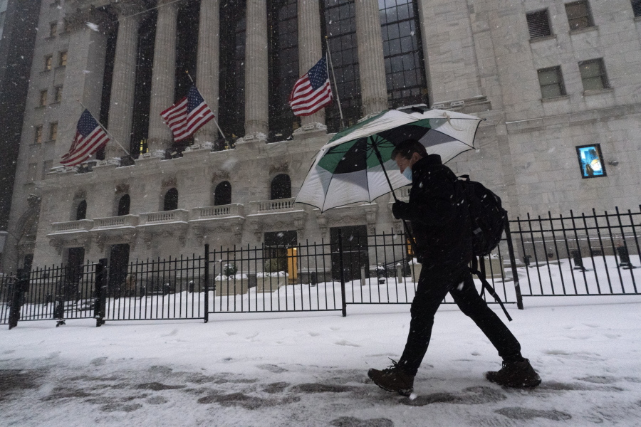 FILE - A man walks past the New York Stock Exchange during a snowstorm, Monday, Feb. 1, 2021, in New York.  Stocks are opening broadly lower on Wall Street and Treasury yields continued to climb. The S&amp;P 500 index gave up 0.8% in the first few minutes of trading Thursday, Feb. 18,  and the tech-heavy Nasdaq was down slightly more, 1.1%.
