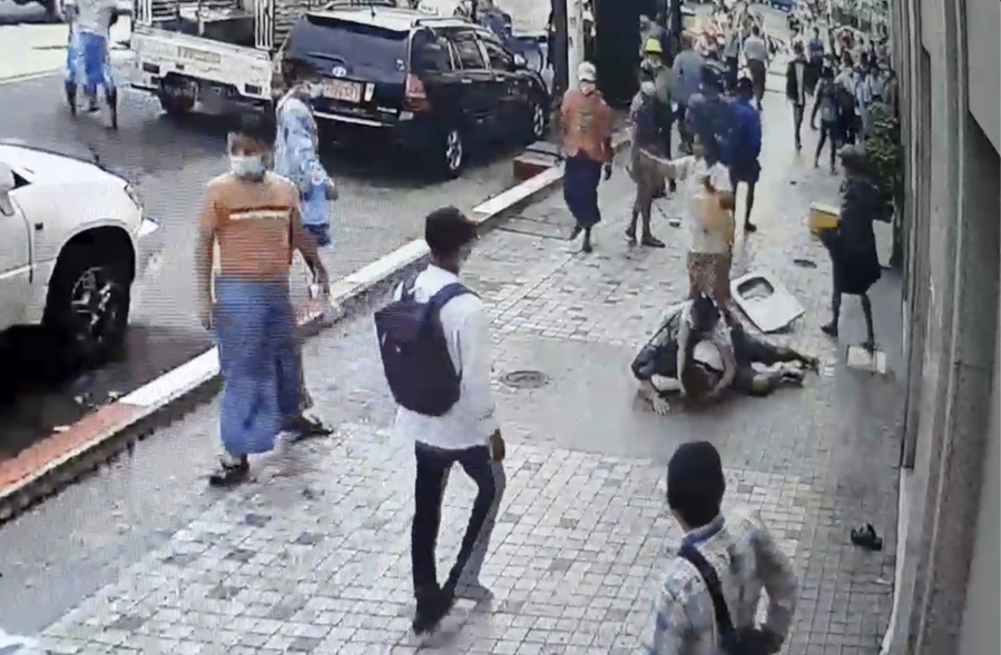 In this image taken from video obtained by Than Lwin Khet News, a woman helps an unidentified man lying on the sidewalk of Sule Pagoda Road after he was attacked by a group of men in Yangon, Myanmar, Thursday, Feb. 25, 2021. Members of a group supporting Myanmar&#039;s military junta have attacked and injured people protesting against the army&#039;s Feb. 1 seizure of power that ousted the elected government of Aung San Suu Kyi.