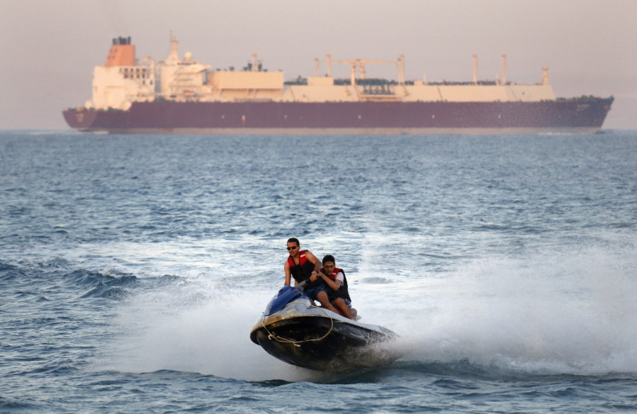 FILE - In this Friday, July 26, 2019 file photo, a ship crosses the Gulf of Suez towards the Red Sea as holiday-makers ride a jet ski at al Sokhna beach in Suez, 127 kilometers (79 miles) east of Cairo, Egypt. Not only are humans changing the surface and temperature of the planet, but also its sounds - and those shifts are detectable even in the open ocean, according to research published Thursday, Feb. 4, 2021.