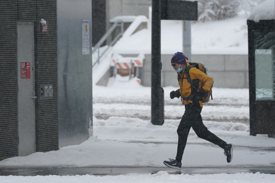 A person runs in the snow, Saturday, Feb. 13, 2021, on the University of Washington campus in Seattle. Winter weather was expected to continue through the weekend in the region.(AP Photo/Ted S.