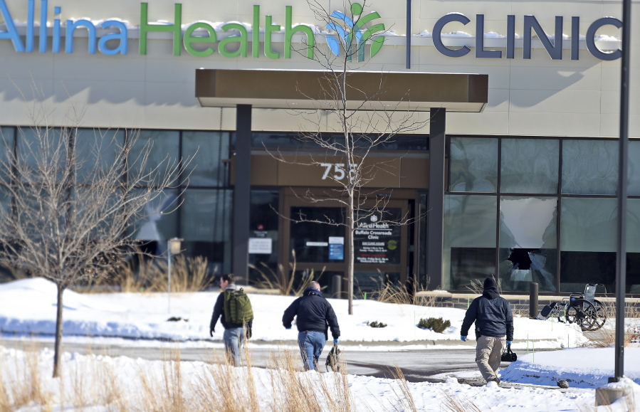 FILE - In this Tuesday, Feb. 9, 2021 file photo, law enforcement personnel walk toward the Allina Health clinic where multiple people were shot in Buffalo, Minn. Doctors say they&#039;re facing increasing threats of violence for refusing to prescribe opioids or trying to wean patients off the addictive painkillers. The issue was underscored by Tuesday&#039;s shooting at the Minnesota clinic.