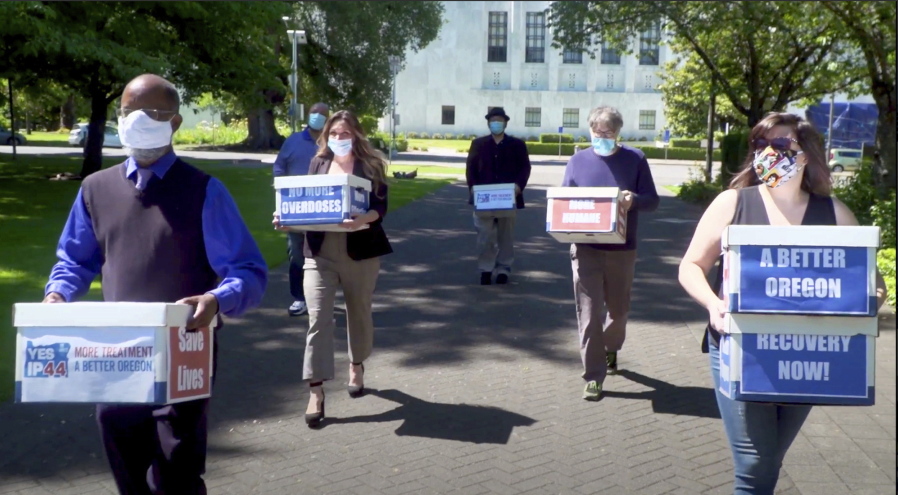 FILE - In this June 26, 2020, file photo taken from video, provided by the Yes on Measure 110 Campaign, volunteers deliver boxes containing signed petitions in favor of the measure to the Oregon Secretary of State&#039;s office in Salem, Ore. The measure said the U.S., possession of small amounts of heroin, cocaine, LSD and other hard drugs would be decriminalized in Oregon. Police in Oregon can no longer arrest someone for possession of small amounts of heroin, methamphetamine and other hard drugs as the ballot measure that decriminalized them took effect on Monday, Feb. 1, 2021.