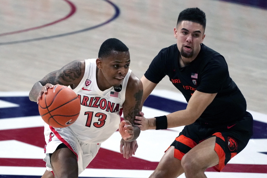 Arizona guard James Akinjo (13) drives by Oregon State guard Jarod Lucas during the first half of an NCAA college basketball game, Thursday, Feb. 11, 2021, in Tucson, Ariz.