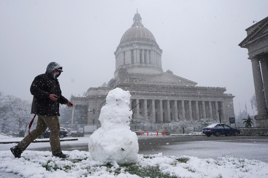 Zach Mayer builds a snowman, Thursday, Feb. 11, 2021, as snow falls at the Capitol in Olympia, Wash. Winter weather is expected throughout the Puget Sound region through the weekend. (AP Photo/Ted S.