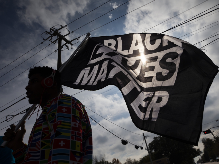 FILE - In this Dec. 12, 2020, file photo, MD Crawford carries a Black Lives Matter flag before a march in La Marque, Texas to protest the shooting of Joshua Feast, 22, by a La Marque police officer. A financial snapshot shared exclusively with The Associated Press shows the Black Lives Matter Global Network Foundation raked in just over $90 million last year.