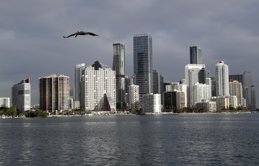 In this Feb. 2, 2018, photo, a pelican flies over Biscayne Bay with the skyline of Miami on the horizon.  Florida is now home to two metro areas with among the highest concentrations of gay and lesbian coupled households in the U.S., according to a new report released by the U.S. Census Bureau. Orlando and Miami had the fourth and sixth highest concentrations of same sex coupled households in the U.S.