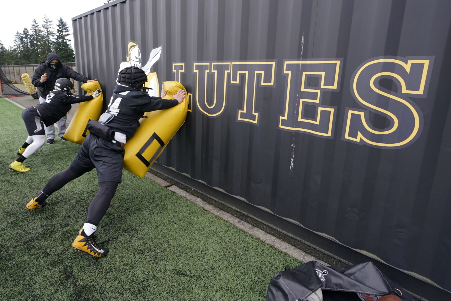 Pacific Lutheran players take part in a blocking drill against a storage container during football practice Tuesday in Tacoma. For all the attention heaped on the FBS level of college football last fall as it tried to play, it will not be the only college football during the 2020-21 sports calendar as a handful of NCAA Division III and NAIA programs begin some form of a winter/spring season Saturday. (Photos by Ted S.