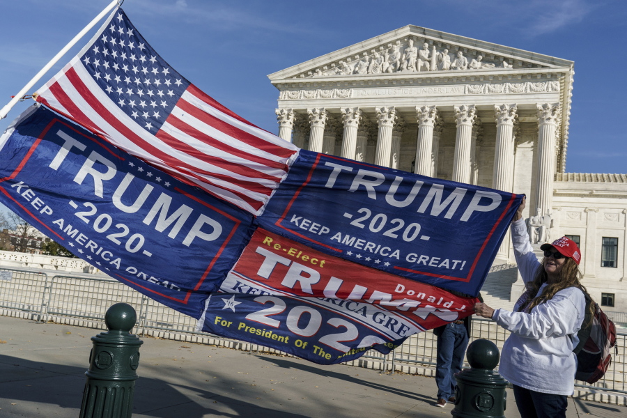 FILE - In this Dec. 11, 2020 file photo, Kathy Kratt of Orlando, Fla., displays her Trump flags as she and other protesters demonstrate their support for President Donald Trump at the Supreme Court in Washington. The Supreme Court has formally rejected a handful of cases related to the 2020 election, including disputes from Pennsylvania that had divided the justices just before the election. The cases the justices rejected involved election challenges filed by former President Donald Trump and his allies in five states President Joe Biden won: Arizona, Georgia, Michigan, Pennsylvania and Wisconsin.(AP Photo/J.