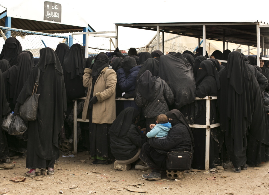 FILE - In this March 31, 2019 file, photo, women residents from former Islamic State-held areas in Syria line up for aid supplies at Al-Hol camp in Hassakeh province, Syria. Killings have surged inside the camp with at least 20 men and women killed in January, 2021. They are believed to be the victims of IS militants trying to enforce their power inside the camp housing 62,000 people, mostly women and children.