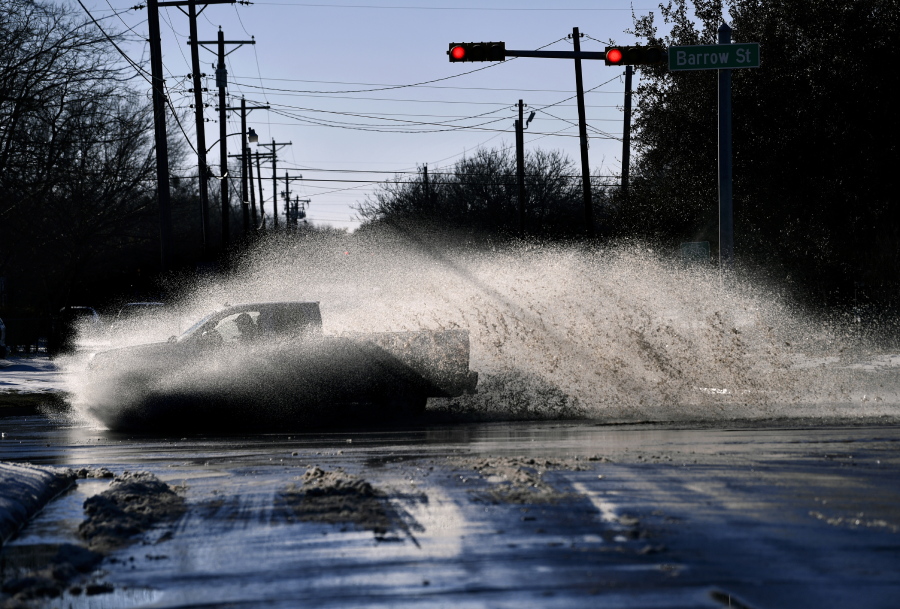 A pickup sends a wake of snow melt high into the air as the driver plows through a large puddle at Barrow and South 11th streets intersection in Abilene, Texas, Friday, Feb. 19, 2021. Temperatures climbed above freezing for the first time since Sunday&#039;s record 14.8-inch snowfall. (Ronald W.