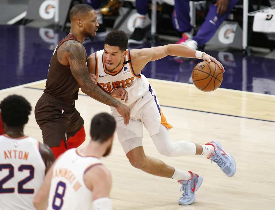 Phoenix Suns&#039; Devin Booker muscles his way towards the basket against Portland Trail Blazers&#039; Damien Lillard during the first half of an NBA basketball game Monday, Feb. 22, 2021, in Phoenix.