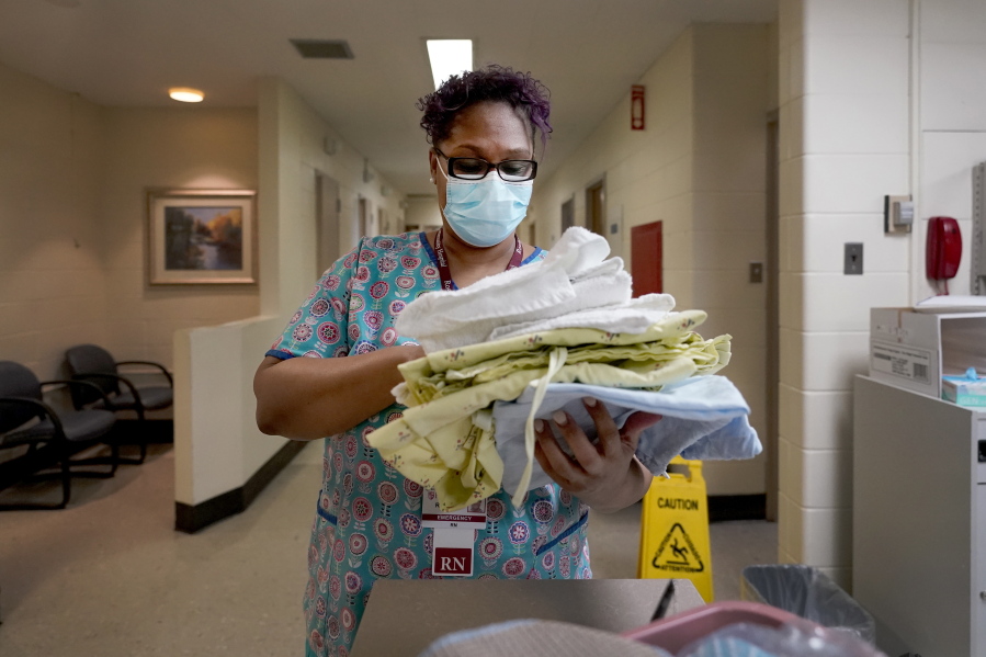 Roseland Community Hospital RN Rhonda Jones, prepares bed linens, towels and a hospital gown Friday, Jan. 29, 2021, for a new patient at the South Side of Chicago hospital. Jones has treated many patients with severe COVID-19, a relative died from it, and her mother and a nephew were infected and recovered, but she is still holding out getting the vaccine.