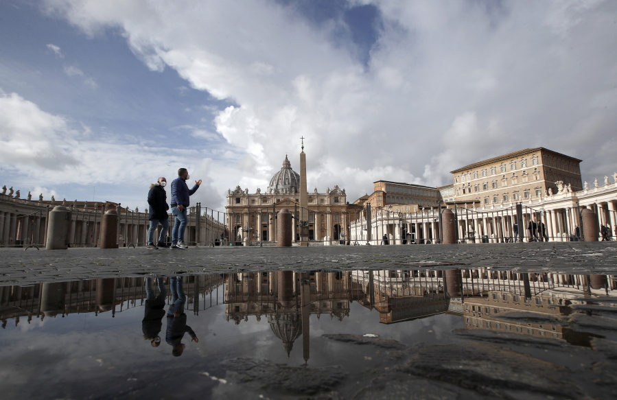 FILE - In this Sunday, Jan. 31, 2021 file photo, people are reflected on a puddle as they walk in St. Peter&#039;s Square, at the Vatican. The Vatican is taking Pope Francis&#039; pro-vaccine stance very seriously: Any Vatican employee who refuses to get a coronavirus shot without valid medical reason risks being fired.