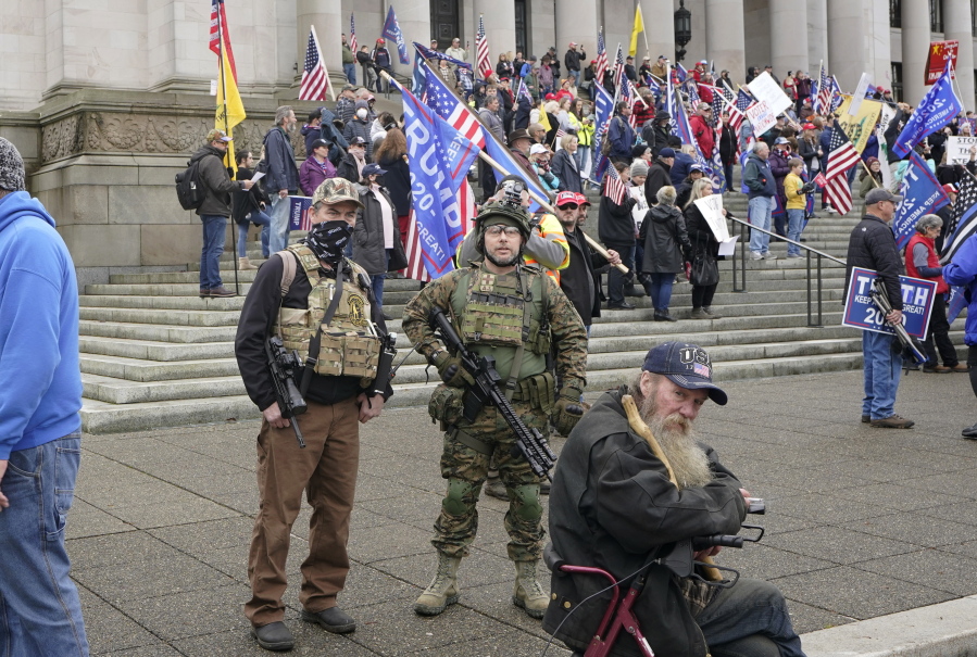 FILE - In this Jan. 6, 2021, file photo at the Capitol in Olympia two men stand armed with guns at a protest supporting President Donald Trump and against the counting of electoral votes in Washington, DC, affirming President-elect Joe Biden&#039;s victory. The open carry of guns and other weapons would be banned on the Capitol campus and at or near any permitted public demonstration across Washington under a measure being considered by Washington lawmakers. (AP Photo/Ted S.
