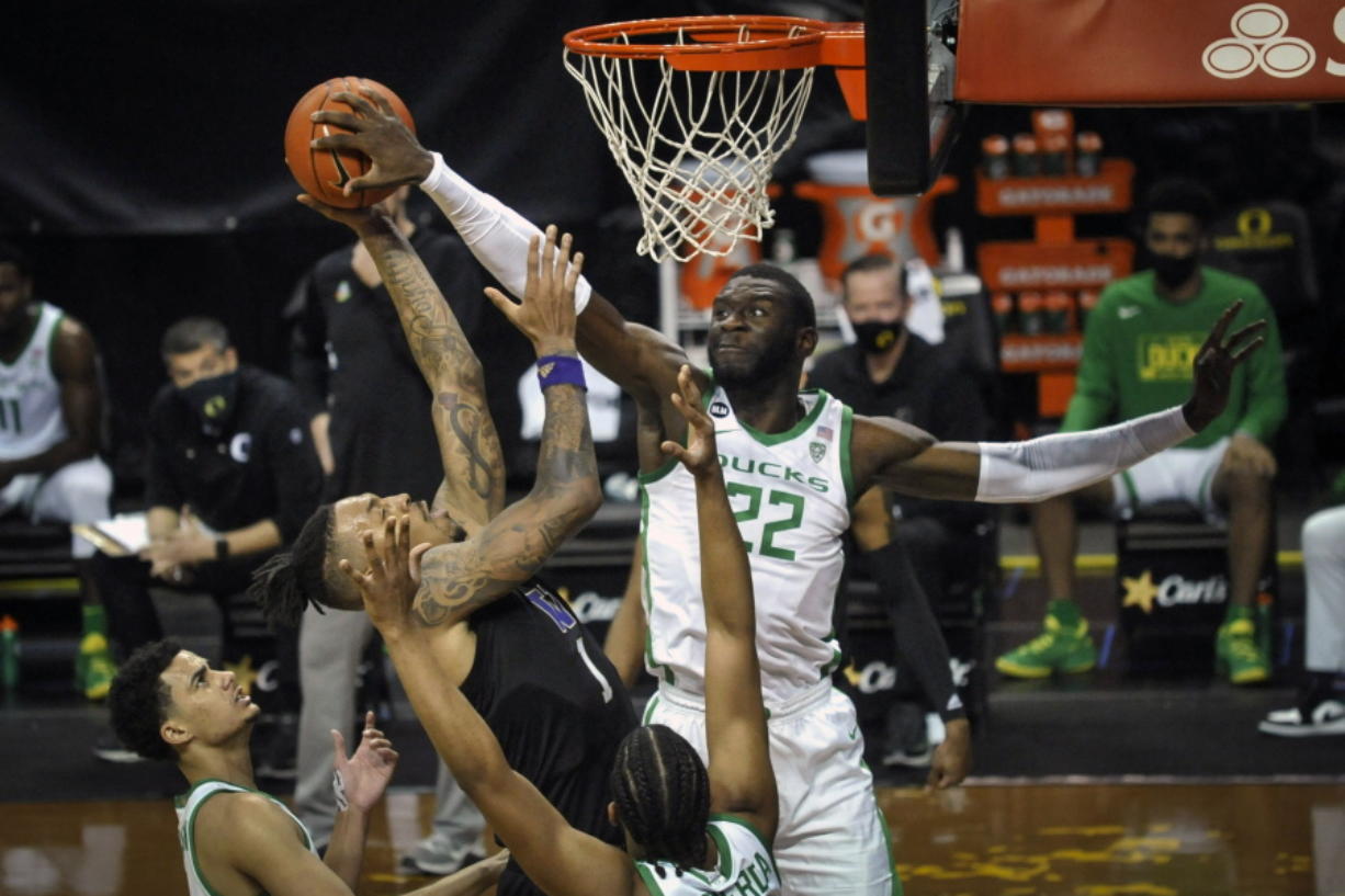 Washington forward Nate Roberts (1) has his shot blocked by Oregon center Franck Kepnang (22) as Oregon guards Will Richardson (0) and LJ Figueroa (12) watch the play during the first half of an NCAA college basketball game Saturday, Feb. 6, 2021, in Eugene, Ore.