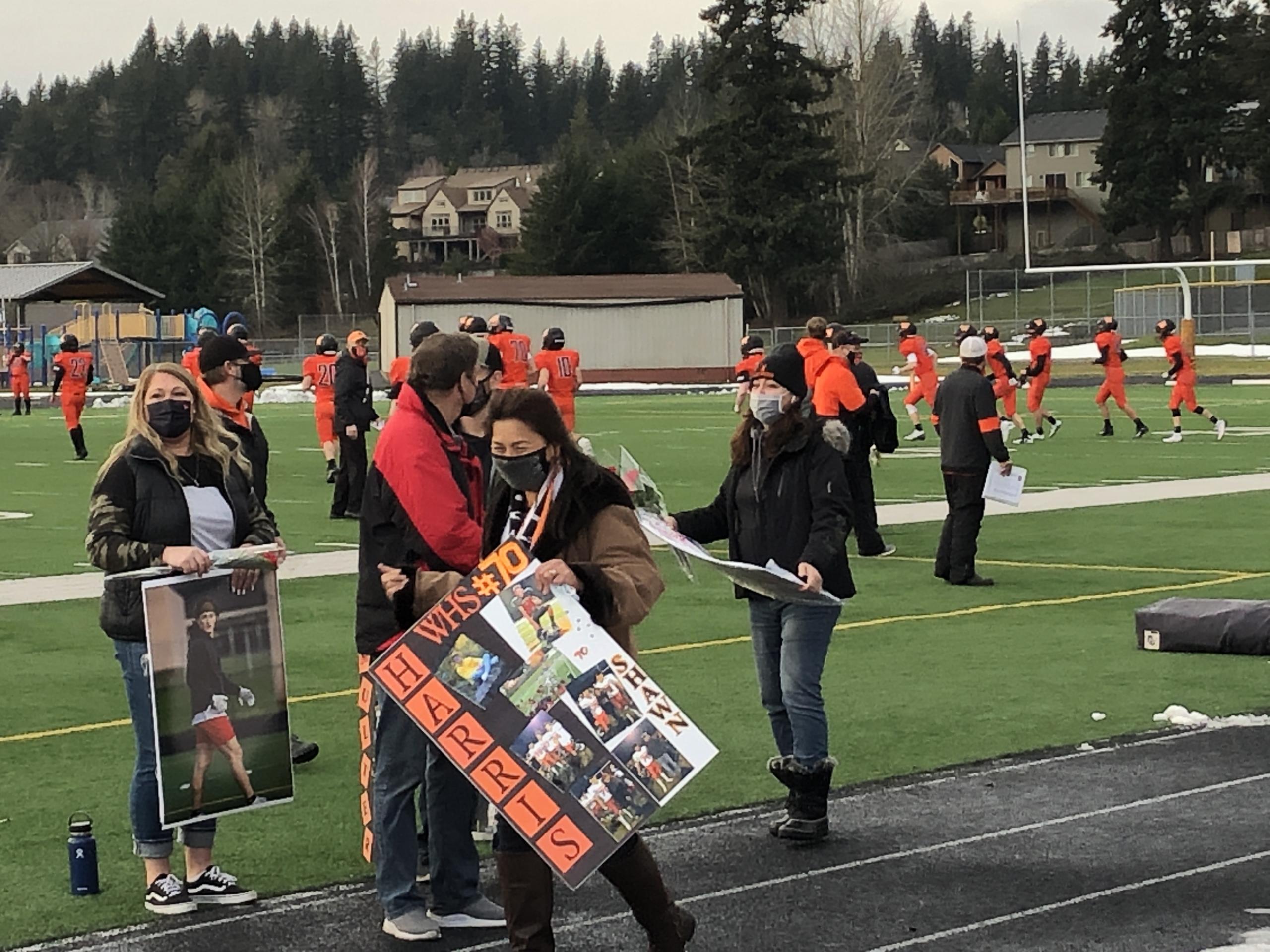Parents of Washougal High School football seniors show special posters before Saturday's game against Mark Morris at Fishback Stadium. With COVID-19 casting uncertainty over the season, Washougal held its Senior Night festivities before its season-opening game Saturday.