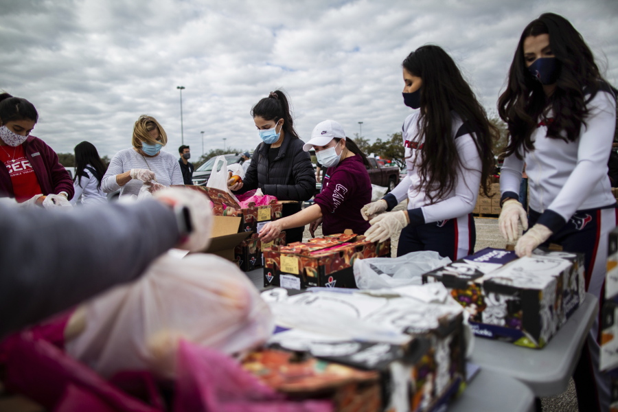 Texans Cheerleaders and other volunteers pack food to distribute to hundreds of people picking up supplies from their cars after frigid temperatures left the Houston area depleted of resources, Sunday, Feb. 21, 2021, in Houston. (Marie D.