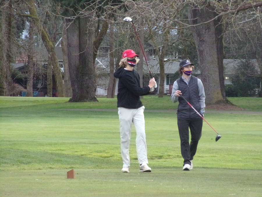 Camas&#039; Eli Huntington, left, hits the ball off the No. 8 tee at Club Green Meadows as Columbia River&#039;s Alden Fay watches on Monday.