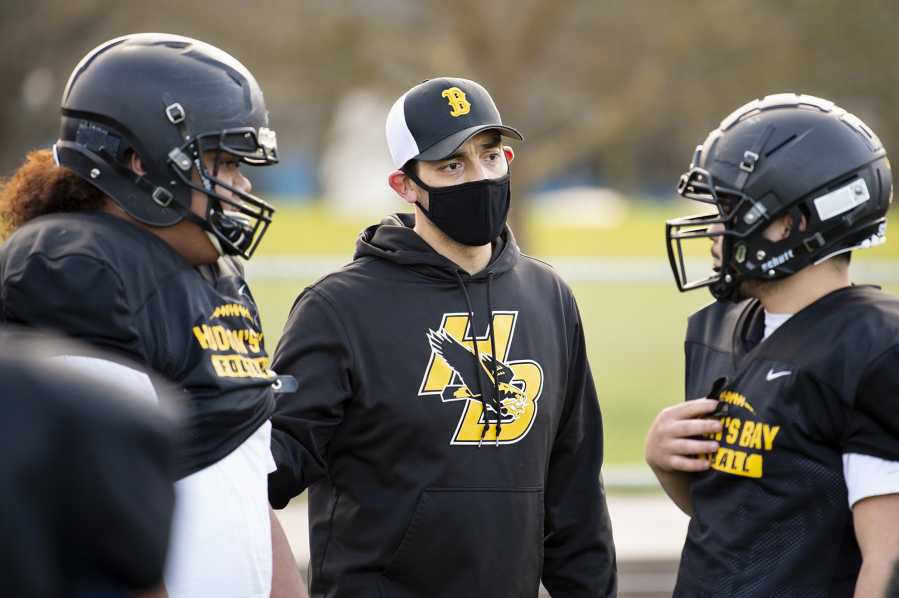 Hudson&#039;s Bay football coach Ray Lions talks to linemen Laufilitonga &#039;Junior&#039; Tamoua and Levi Mikaele at a recent practice. The Eagles have formed a unique bond through their shared experiences, and coach Ray Lions has embraced and cultivated the family-like atmosphere.