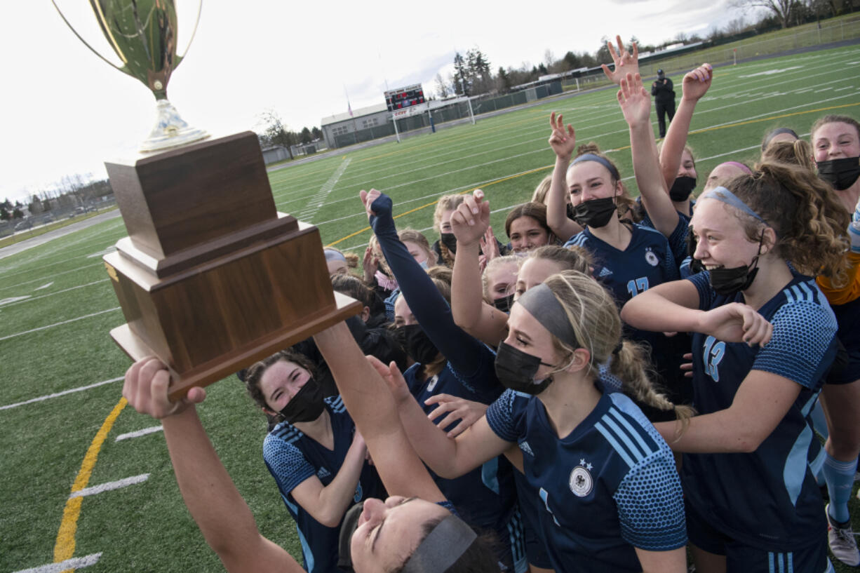 Hockinson senior Kendall McGraw, bottom, lifts the district championship trophy in the air as her team swarms her after the 2A Southwest District Championship on Saturday, March 20, 2021, at District Stadium in Battle Ground. Hockinson won 2-0 to complete a perfect 11-0 season.