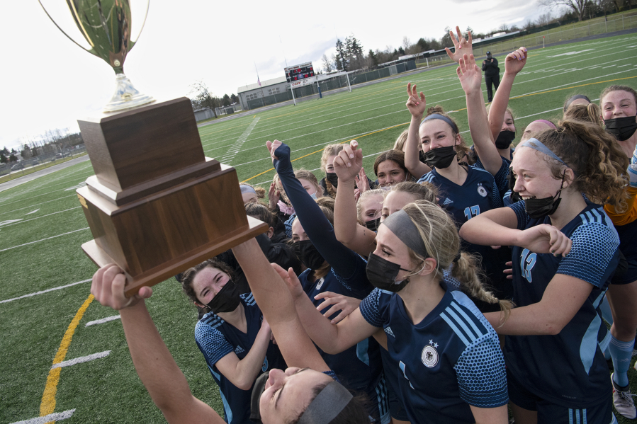 Hockinson senior Kendall McGraw, bottom, lifts the district championship trophy in the air as her team swarms her after the 2A Southwest District Championship on Saturday, March 20, 2021, at District Stadium in Battle Ground. Hockinson won 2-0 to complete a perfect 11-0 season.