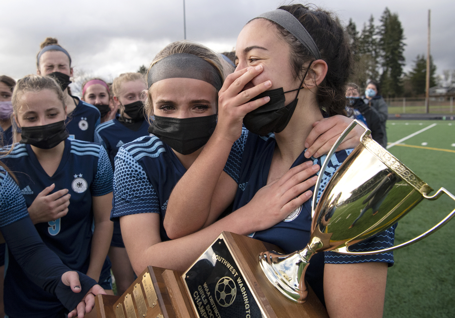 A teary-eyed Hockinson senior Kati Waggoner hugs Kendall McGraw, who holds the 2A Southwest District Championship trophy on Saturday, March 20, 2021, at District Stadium in Battle Ground. Hockinson won 2-0 to complete a perfect 11-0 season.